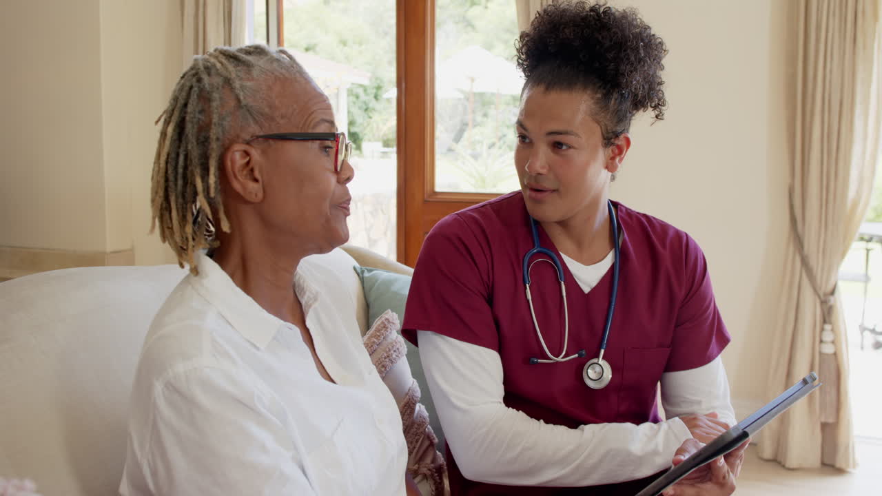 Healthcare professional in scrubs discussing care plan with senior woman at home
