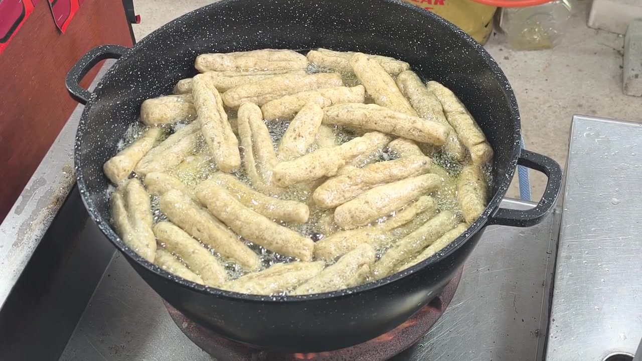 Keropok lekor sfrigolante fritto alla perfezione in olio bollente. Questo tradizionale snack malese di cracker di pesce di Terengganu è fatto con una gustosa miscela di pasta di pesce e farina.