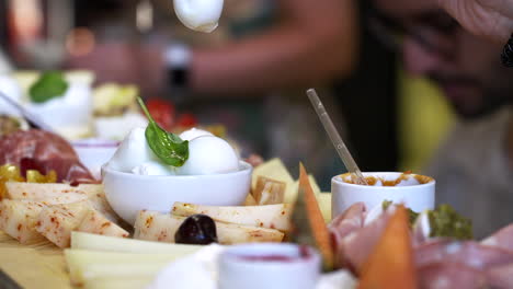 restaurante gastronómico cena buffet y aperitivo, hors d&#39;oeuvre y surtido de varios aperitivos, prosciutto de queso mozzarella, fondo borroso la mano de la mujer toma un trozo de mozzarella con tenedor