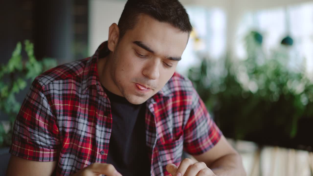 a man in a plaid shirt is eating delicious pizza at a pizzeria in the afternoon
