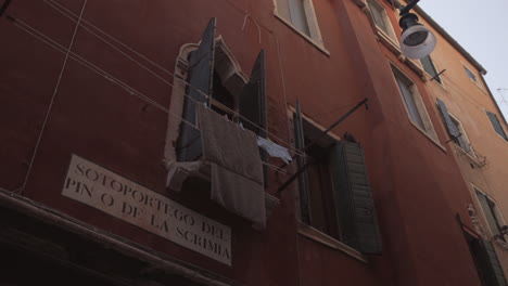 toallas secas colgadas frente a una ventana en un edificio rojo en venecia, italia