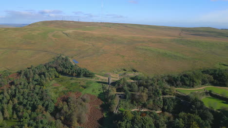 Einsames-Steinturmgebäude-Am-Hang,-Langsame,-Weite-Umlaufbahn-Mit-Hohem-Funkmast-Auf-Dem-Hügel-Dahinter