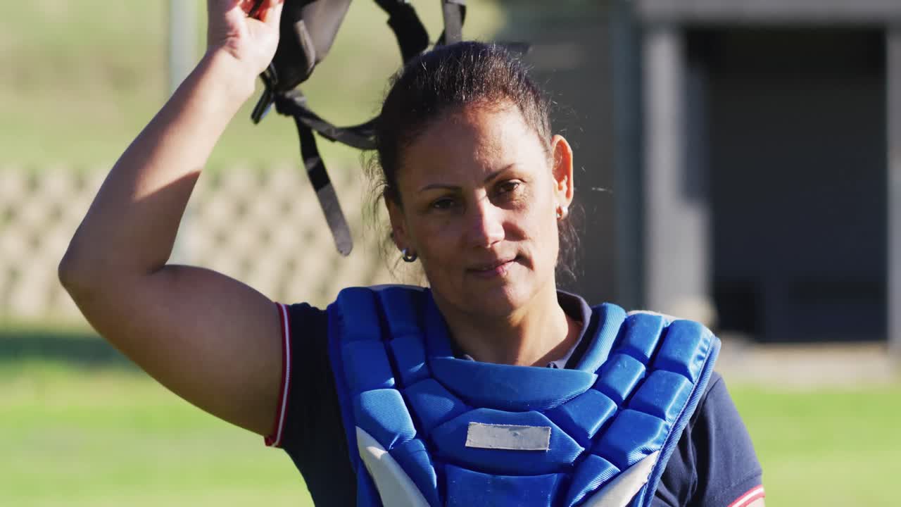 retrato de una feliz jugadora de béisbol caucásica en el campo, quitándose el casco y sonriendo