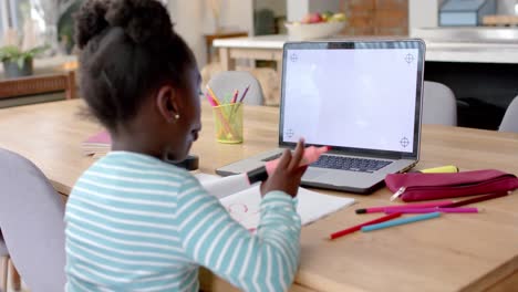 Niña-Afroamericana-Aprendiendo-En-Línea-En-La-Mesa-Usando-Una-Computadora-Portátil-Con-Espacio-Para-Copiar-En-La-Pantalla,-Cámara-Lenta