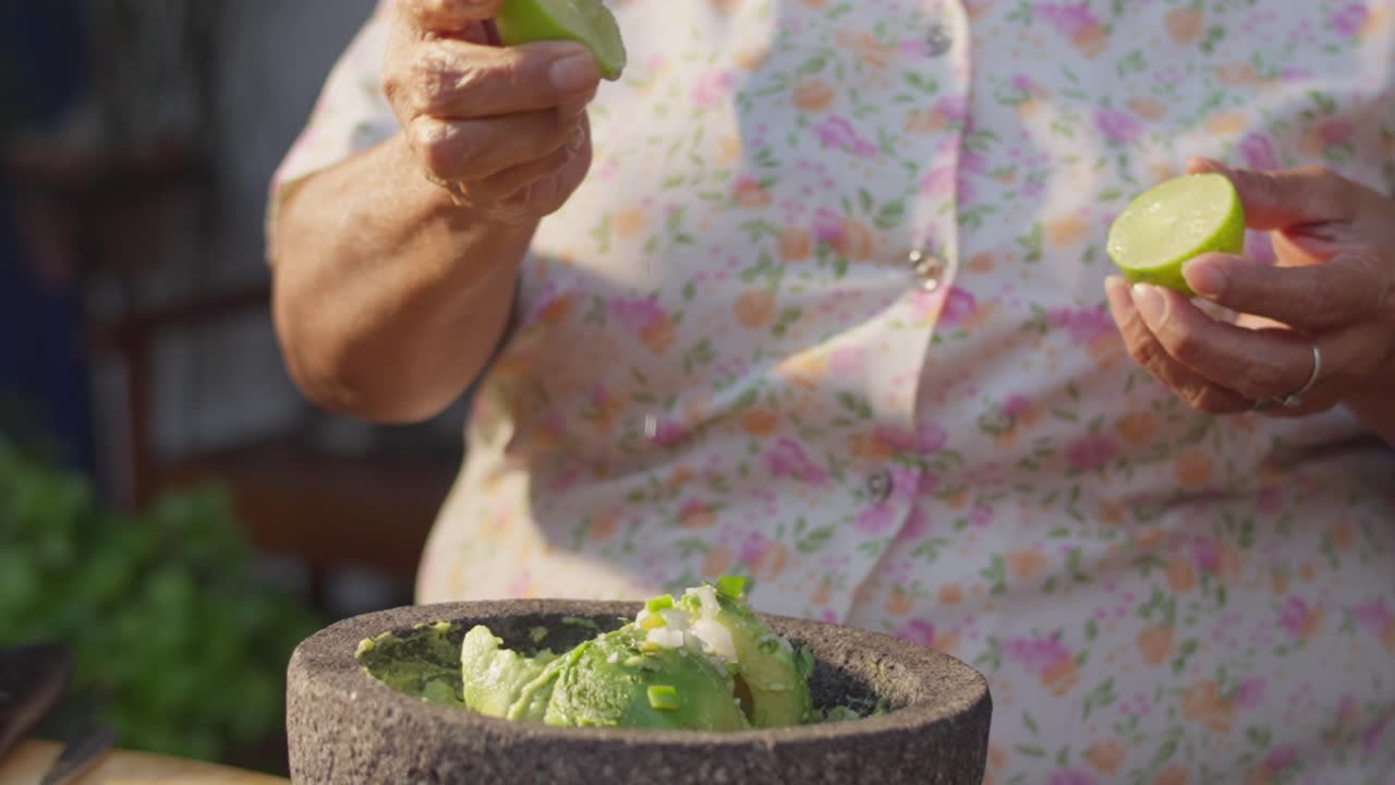 SLOW MOTION SHOT OF A WOMAN ADDING LEMON TO A GUACAMOLE