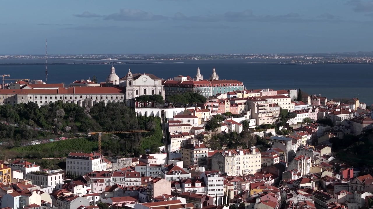 Punto panoramico Miradouro da Graça in cima alla collina con l'estuario del fiume Tago, edifici tradizionali portoghesi con tetti di tegole, Lisbona. Aerea.