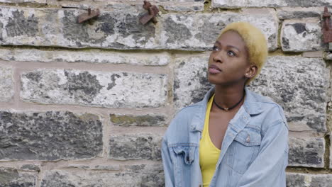 portrait of a trendy, young, woman relaxing by a brick wall