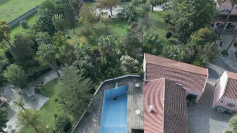 Aerial-view-from-orbit-of-an-empty-swimming-pool-with-large-green-fields-near-of-Lisbon,-Portugal