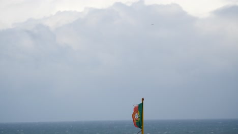 bandera portuguesa con cielo, nubes y océano en el fondo