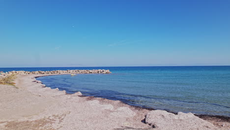 costa tranquila con aguas azules claras y formación rocosa a la luz del día