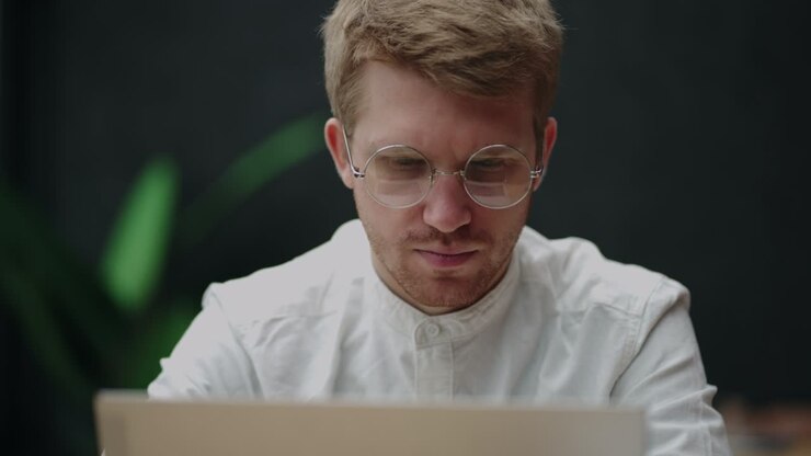 handsome european man is reading news on screen of laptop in home or in office, portrait of thinking face expression