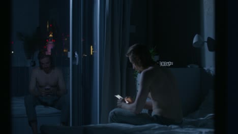 man using a smartphone in his bedroom at night