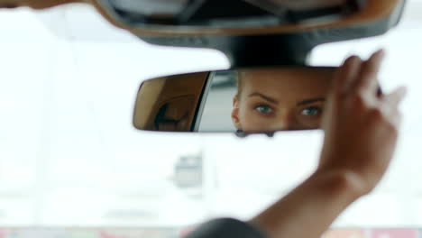 Serious-woman-adjusting-rear-view-mirror.-Woman-sitting-behind-steering-wheel