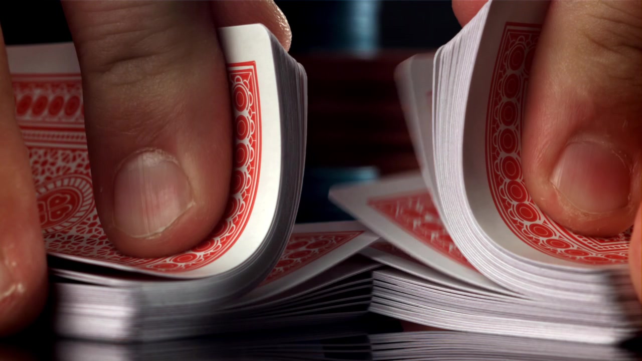 Primo piano di mani che mescolano un mazzo di carte da gioco rosse