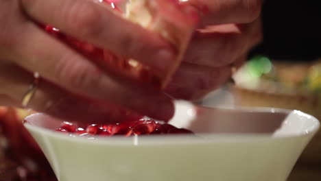 Woman-hands-removes-seeds-from-the-pomegranate