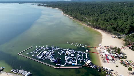 Aquapark-Biscarrosse-France-with-slides,-trampolines-and-climbing-frames-floating-over-water,-Aerial-pan-right-shot