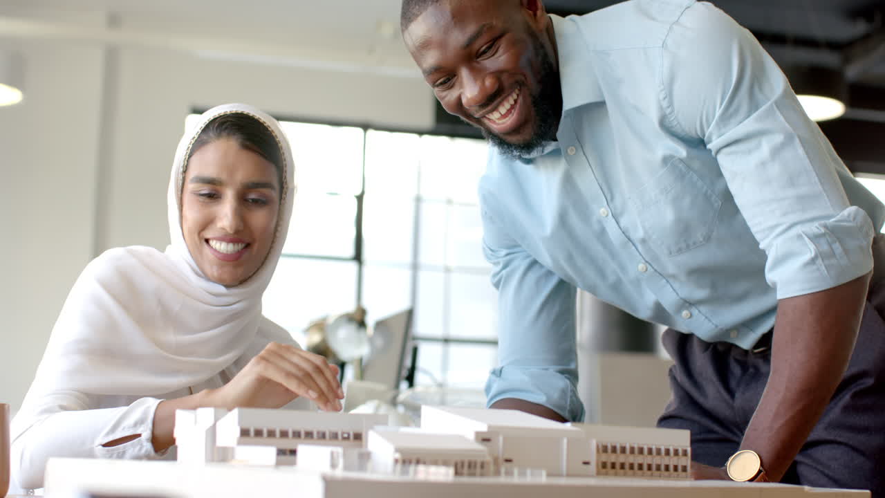 Collaborating on architectural model, diverse colleagues discussing project in modern office