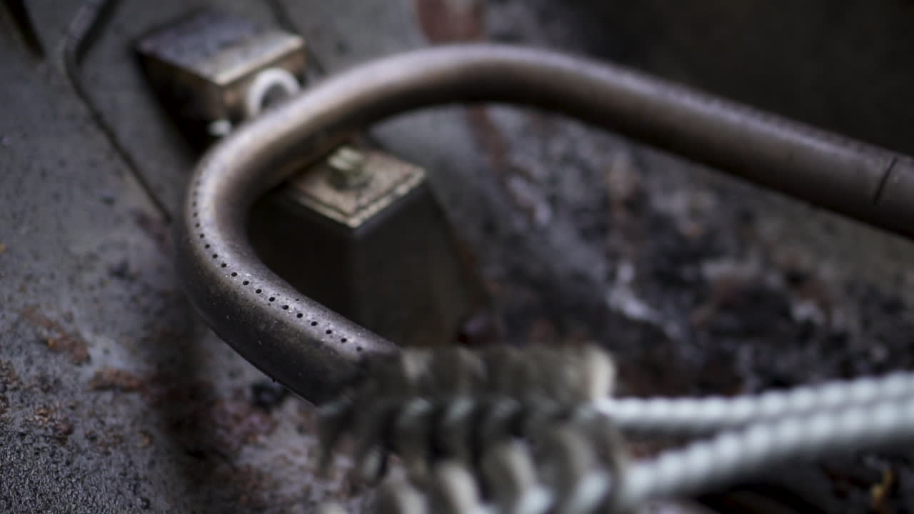 крупным планом очистка металлической горелки газового гриля проволочной щеткой перед приготовлением барбекю