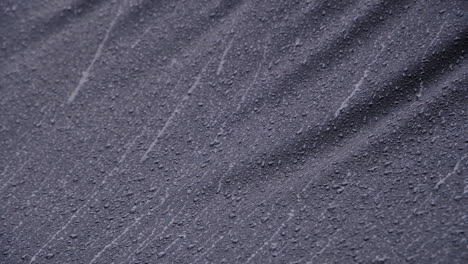 Fuertes-Lluvias-Cayendo-Sobre-Textiles-Impermeables-Negros.-4k