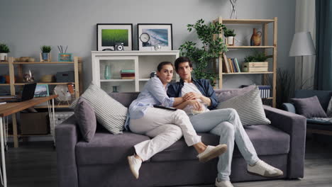una pareja relajándose en casa viendo una película.