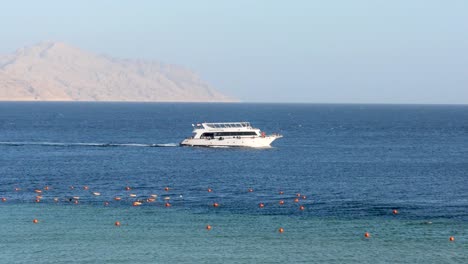 Yacht-crusing-on-the-sea-with-desert-sandy-island-in-the-background,-Red-Sea,-Sharm-El-Sheikh,-Egypt