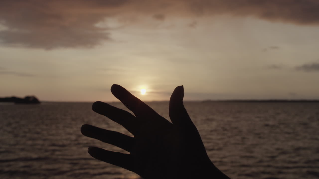 Silhouette Of A Hand In Front Of The Sunset at the Pacific Coast in Buenaventura, Colombia