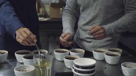 Dos-Hombres-Sumergiendo-Cucharas-En-Tazas-De-Café