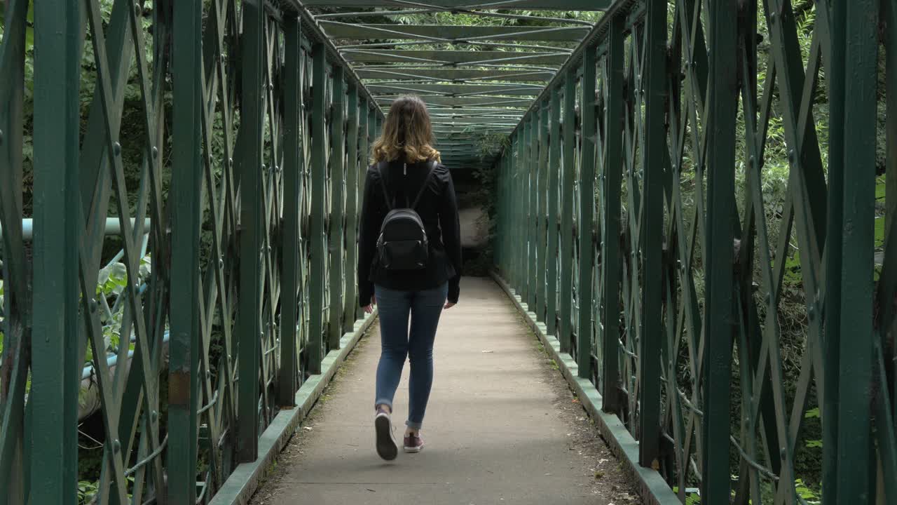 Caucasian girl walking on bridge. Leading lines, city break, day trip