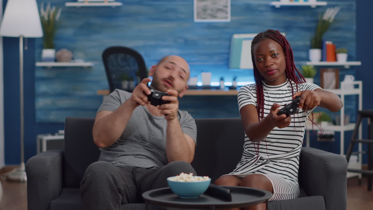 Modern interracial couple playing video game on TV