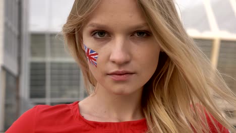 portrait of a young blonde girl soccer fan of england looking into the camera, serious face, stadium in the background 50 fps