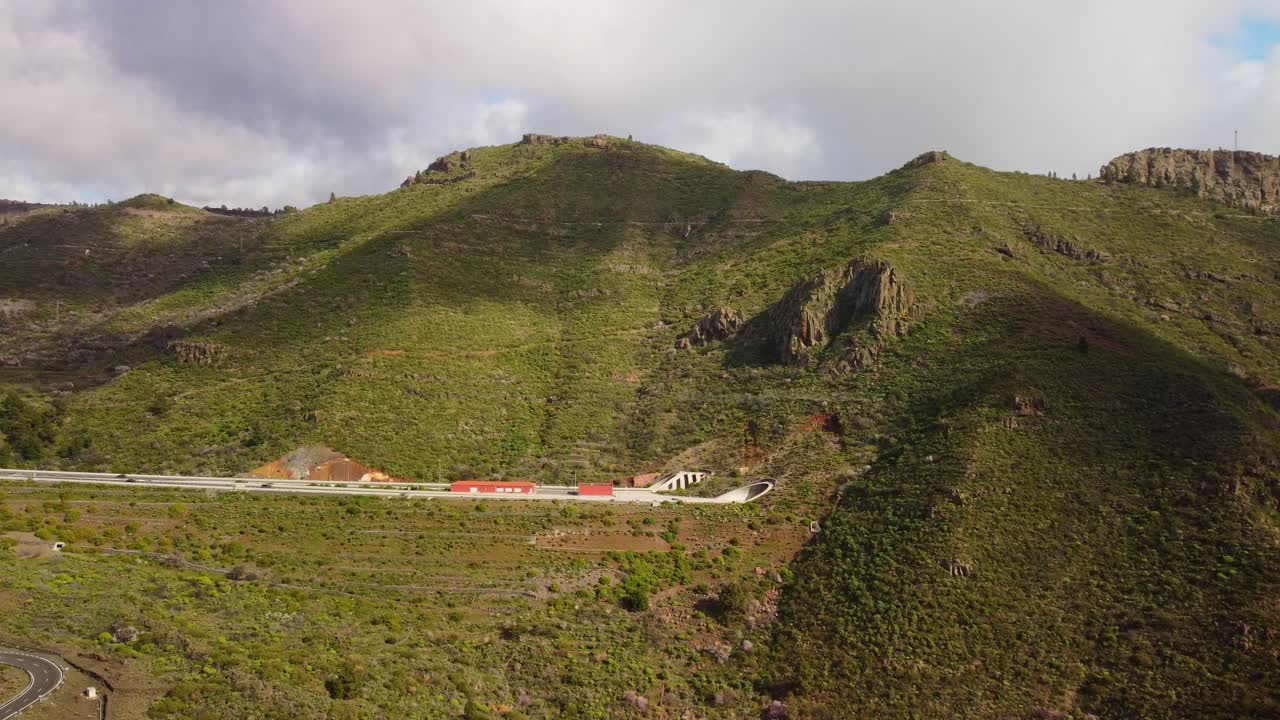 coches en la carretera conduciendo en un túnel en altas montañas verdes
