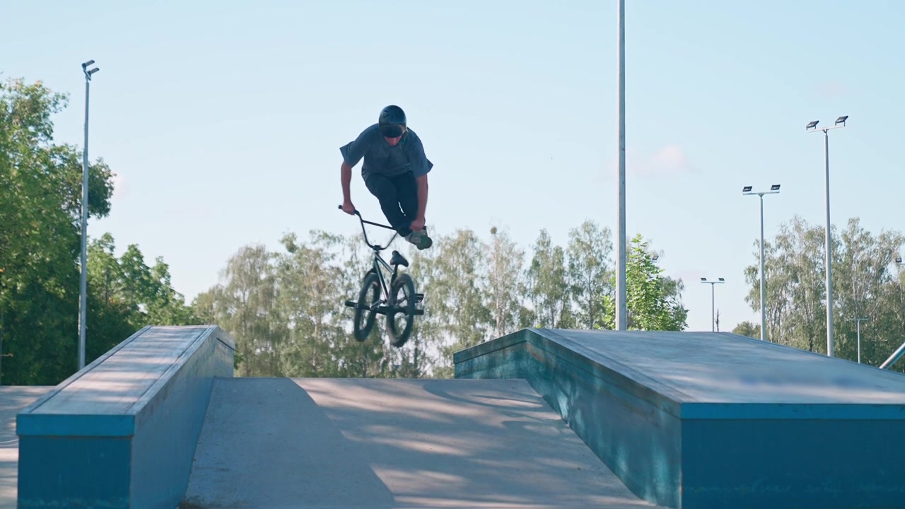 Ung mand på BMX-cykel hopper på en rampe i en skatepark