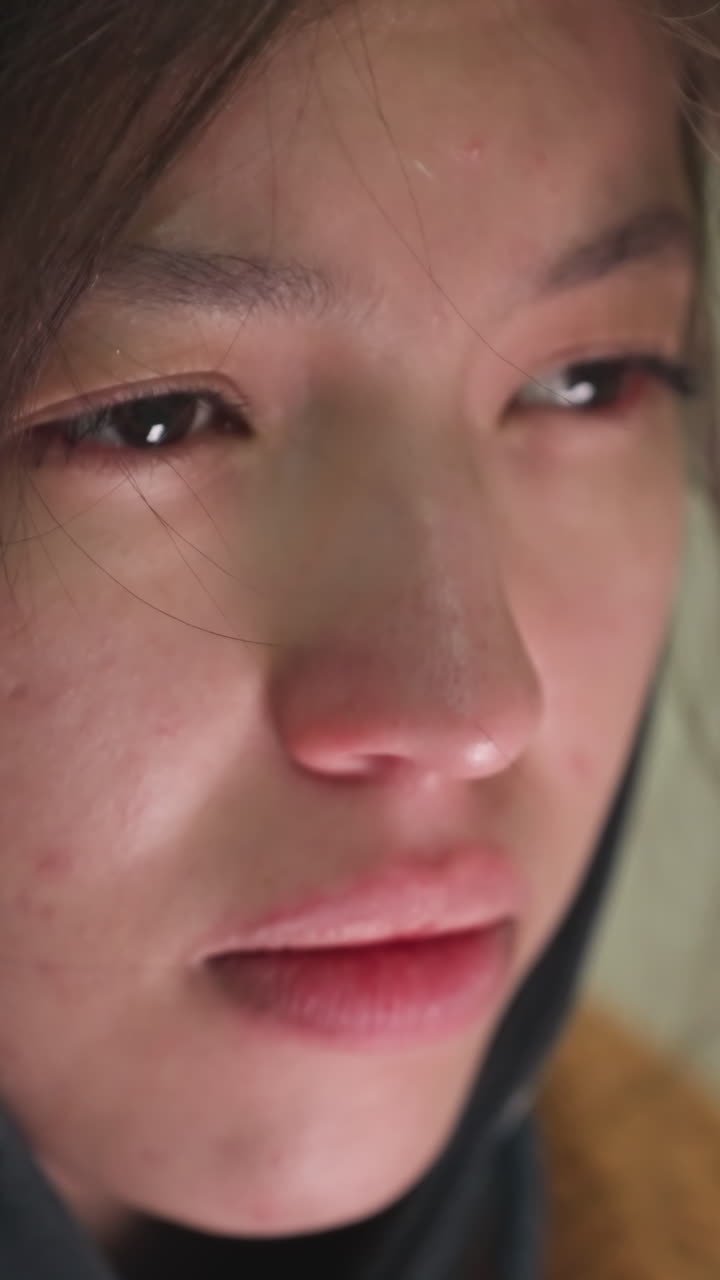 어린 소녀의 얼굴의 클로즈업, 그녀의 머리카락은 약간 망진창, 깊은 우울한 표정으로, 그녀의 눈은 아래로 던져져, 걱정과 성찰의 상태를 반영합니다.