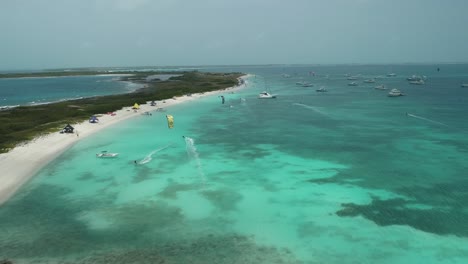 kite surfers ride on clear blue ocean water above reefs, crasky los roques, aerial dolly