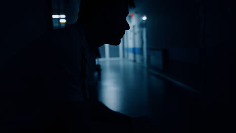 nervous man rubbing hands and face while expecting in the hospital hall. worried husband waiting in the corridor during labour. side view.