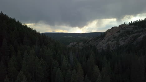 Aerial-View-of-Storm-Clouds-Looming-in-the-Distance-in-the-Forested-Mountains-of-Colorado,-Backwards-Motion