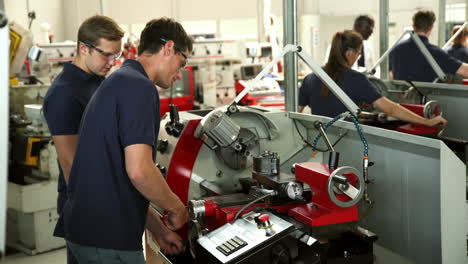 apprentice engineers using machinery in manufacturing plant