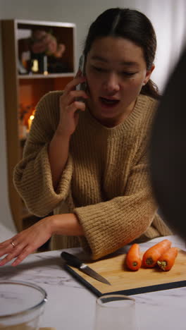 vertical video of woman talking on mobile phone at home preparing fresh vegetables for meal on counter in kitchen 2