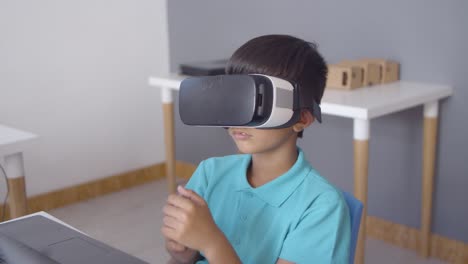 schoolboy wearing vr glasses sitting at desk