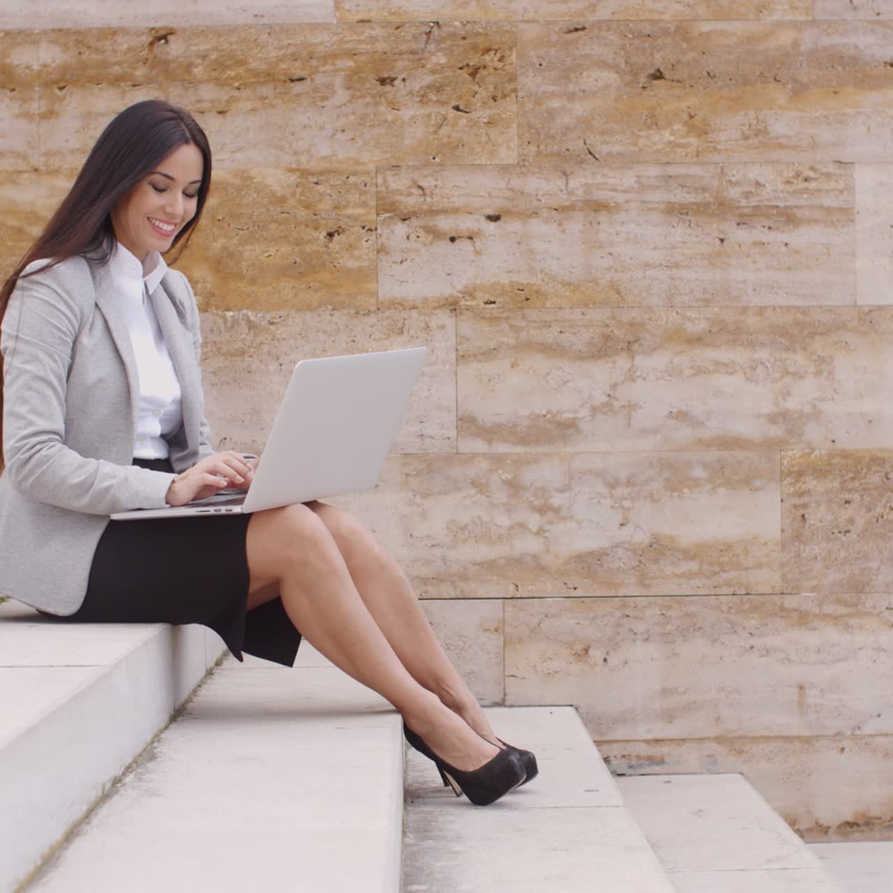 Donna ripresa dal basso che usa il laptop all'aperto