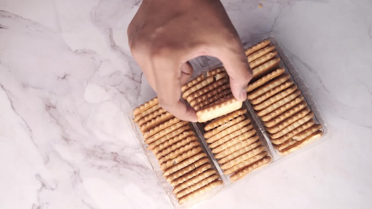 Hand reaching for crackers from a plastic container
