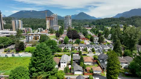 Volar-Sobre-Residenciales-En-Lynnmour-Con-Bosques-Y-Montañas-Al-Fondo-En-El-Norte-De-Vancouver,-Canadá