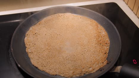 panqueque de trigo sarraceno cocinando en una sartén de hierro fundido caliente