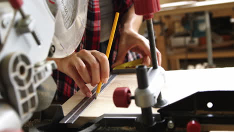 Focus on carpenter hands drawing on wooden plank