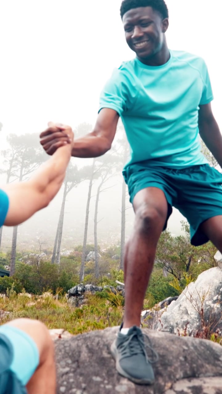 Two Men Helping Each Other Hike Up a Rocky Mountain Trail