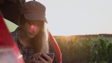 Ein-Junges-Mädchen-Sitzt-Im-Kofferraum-Eines-Autos-Und-Benutzt-Ein-Smartphone.