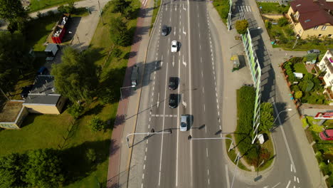 inclinación aérea hacia arriba en un vecindario suburbano verde con intersección y autos en el semáforo