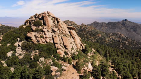 Primer-Plano-Aéreo-De-Un-Afloramiento-De-Montaña-Rocosa-Del-Desierto-Con-Más-Montañas-En-El-Fondo