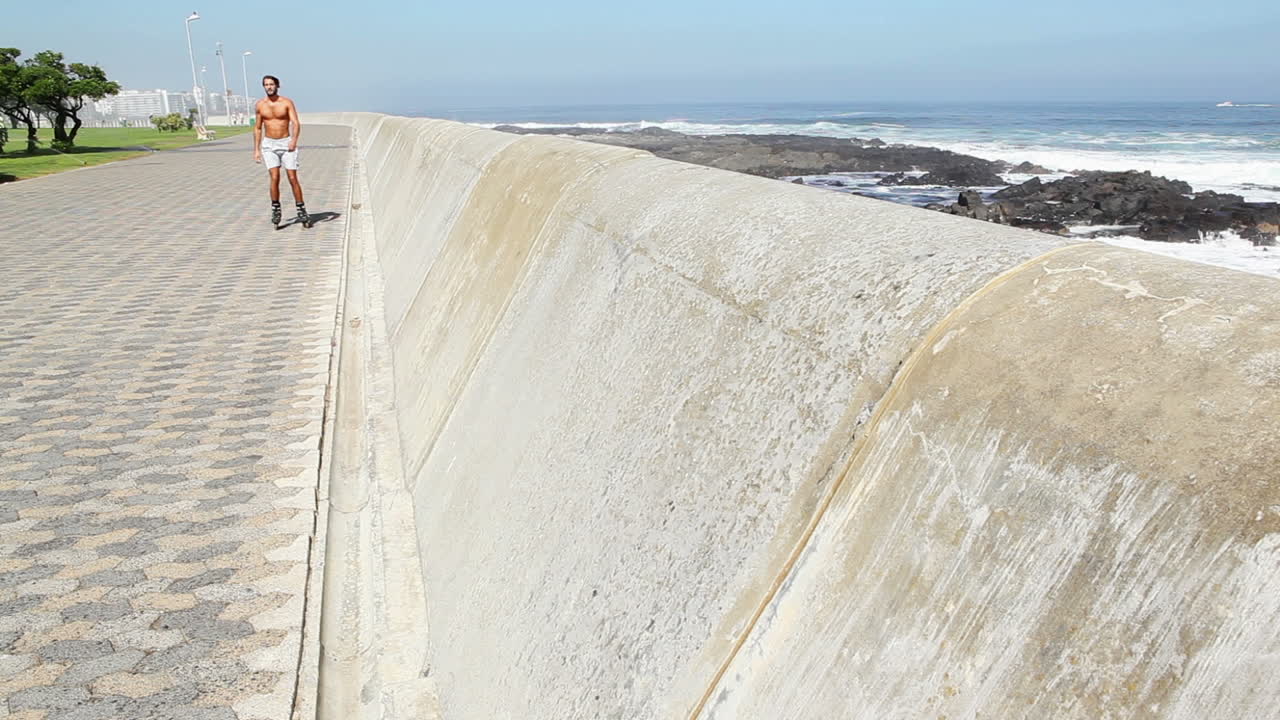 Hombre en forma patinando en línea por la costa