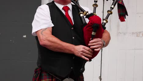 man playing bagpipes in traditional scottish attire